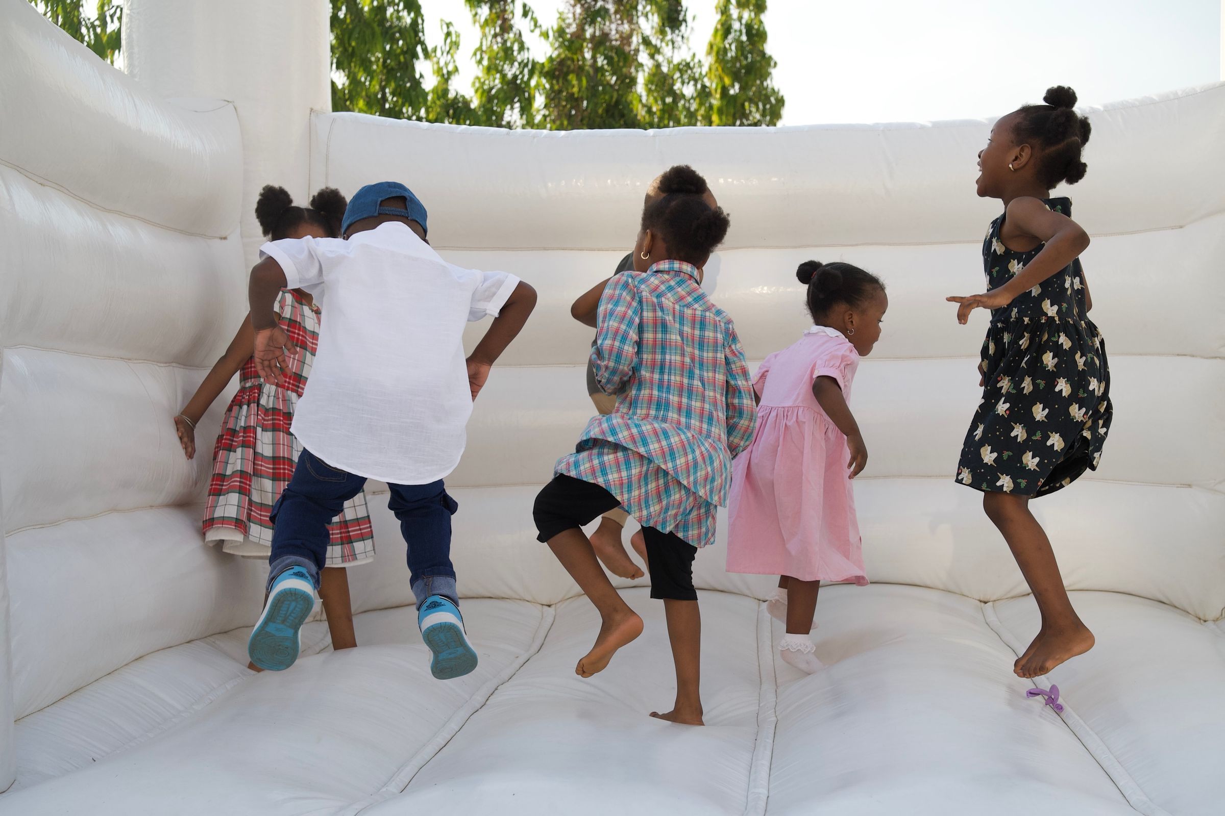 Kids climbing and playing on a bounce house in a backyard